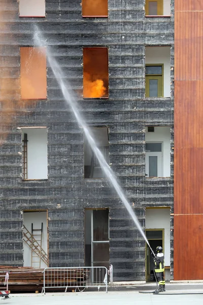 Bombero con la boquilla apaga el fuego — Foto de Stock