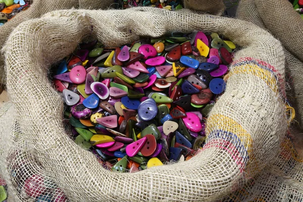 Jute bag full of buttons made with colored palm seeds — Stock Photo, Image