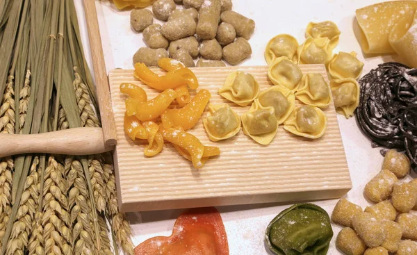 Cutting board with ravioli and fresh pasta with black cuttlefish — Stock Photo, Image