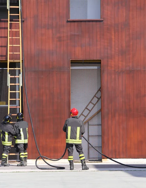 Bomberos en la brigada de bomberos con una larga escalera —  Fotos de Stock