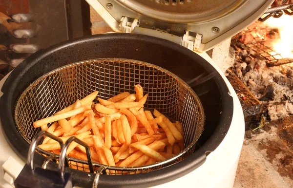 Friteuse avec de nombreuses pommes de terre frites près de la cheminée — Photo