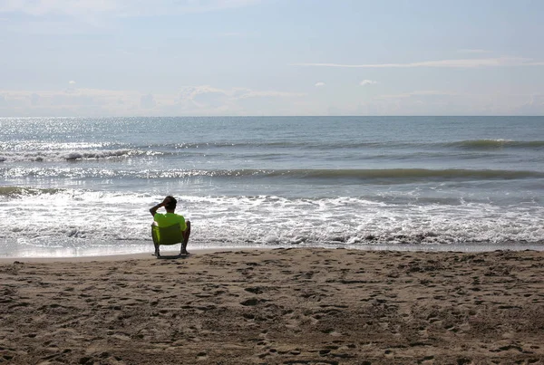 Niño solitario en la orilla del mar de verano descansa —  Fotos de Stock