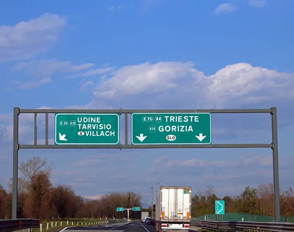 Estrada italiana com o sinal de estrada com direções para Udine e — Fotografia de Stock