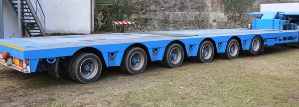 Очень длинный синий грузовик с шестью осями колес — стоковое фото