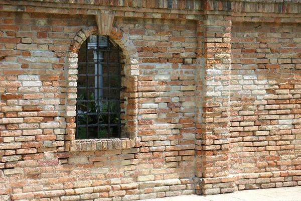 Medieval Window with metallic grating in the middle of the brick — Stock Photo, Image