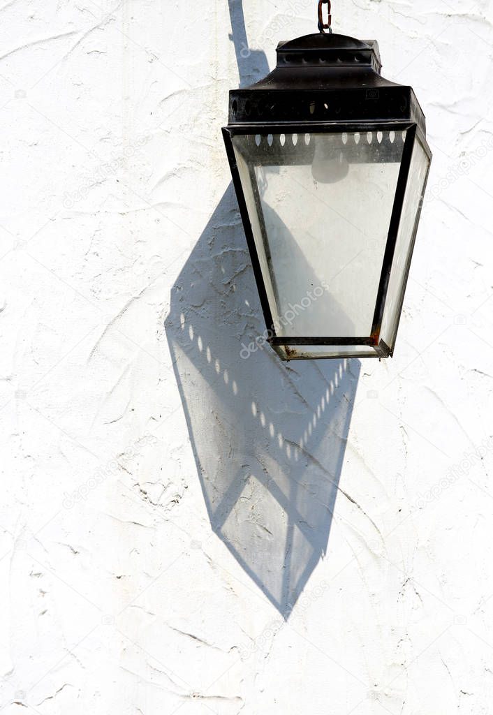 ancient lamp with glass and the shadow on the white wall of the 