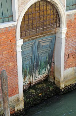 rotten wooden gate on a canal of the island of Venice clipart