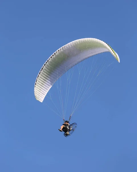 wide Motor powered hang glider flies high in the blue sky