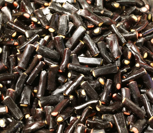 Pieces of black licorice with colored sugary stuffing — Stock Photo, Image