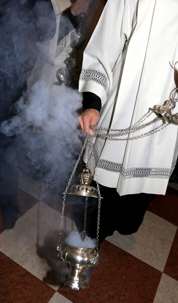 Christian priest blessing with incense during Holy Mass