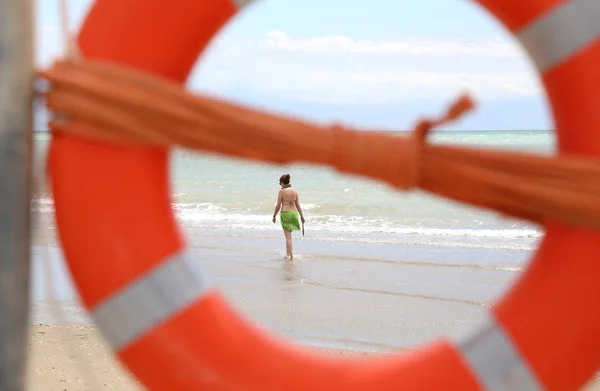 Pomarańczowy życia boja z liny ratunkowej i kobieta na plaży — Zdjęcie stockowe