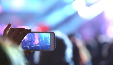Genç kız bir fotoğraf ile smartphone konser sırasında alır.