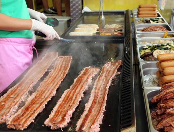 Embutidos cocinados en el plato caliente en un puesto de comida de la calle — Foto de Stock