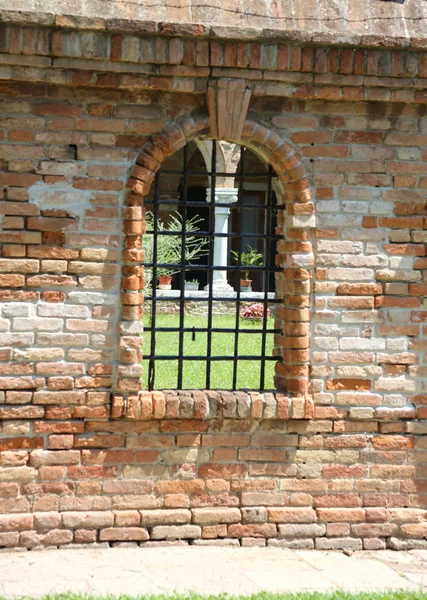 Medieval Window with metal grating in the middle of the brick wa — Stock Photo, Image