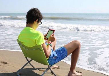 ebook ve şort sahilde bir çocuk