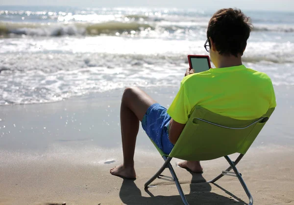 Young boy with ebook on seashore in summer — Stock Photo, Image