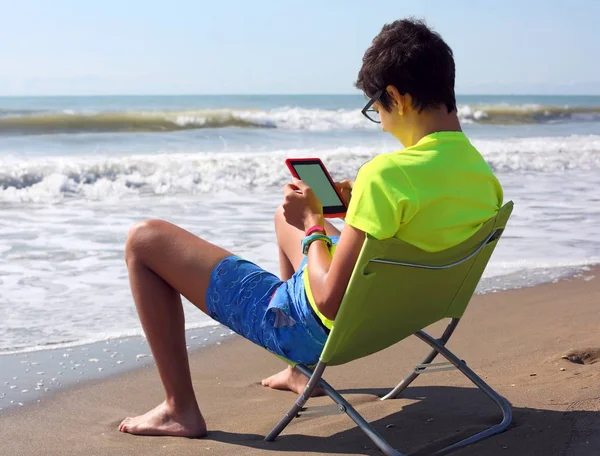 電子ブックと夏のビーチで短パンの少年 — ストック写真