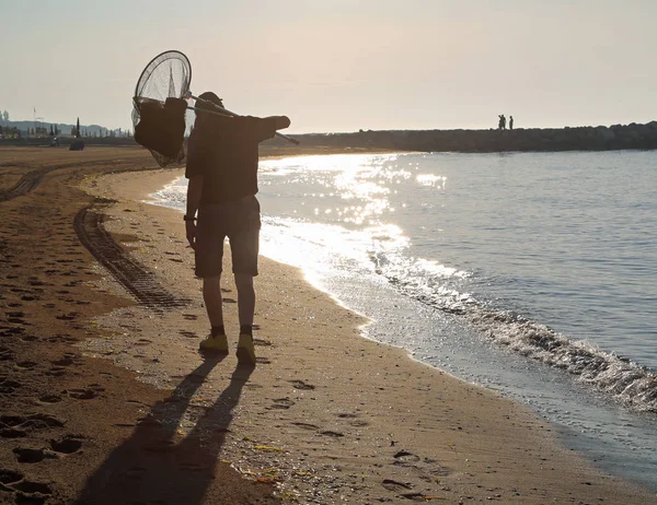 Rybak z sieci spacery nad brzegiem morza o świcie — Zdjęcie stockowe