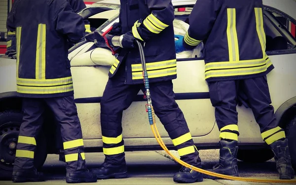 Bomberos valientes aliviar a un herido después de un accidente de tráfico con —  Fotos de Stock