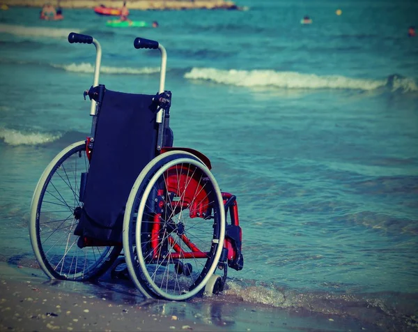 Fauteuil roulant sur le rivage par la mer — Photo