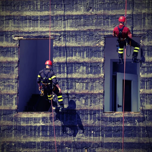 Escaladores de bombeiros que escalam uma parede — Fotografia de Stock