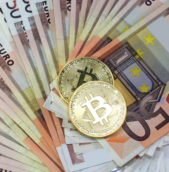 Two golden BitCoin coins over a lot of euro banknotes — Stock Photo, Image