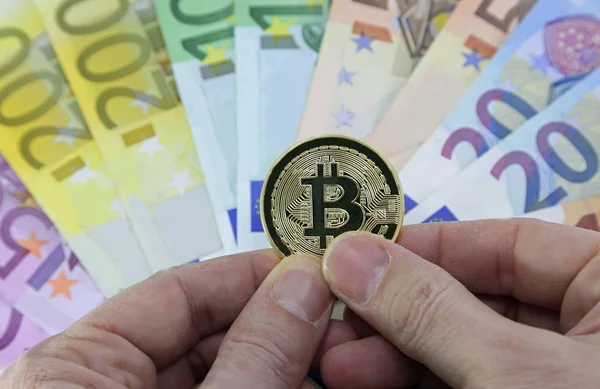 Mano con bitcoin dorato e banconote europee — Foto Stock