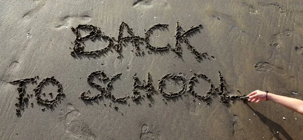 Volver a la escuela grande escrito en la arena con la mano — Foto de Stock