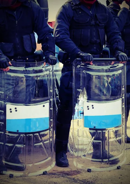 Bereitschaftspolizisten mit Schlagstöcken und Schutzschilden bei Sicherheitskontrollen durch — Stockfoto