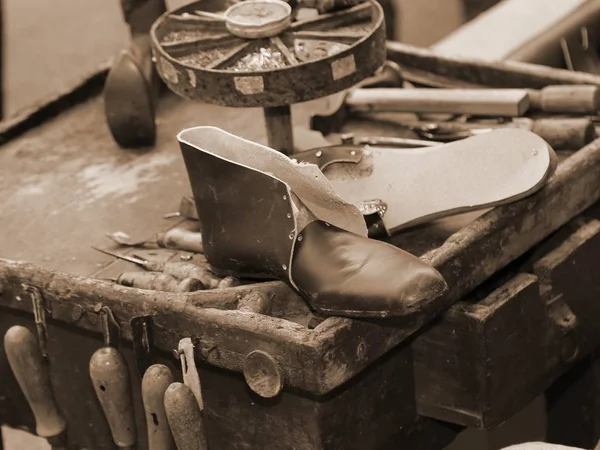 Oficina de um sapateiro artesão com um sapato de couro com sépia — Fotografia de Stock