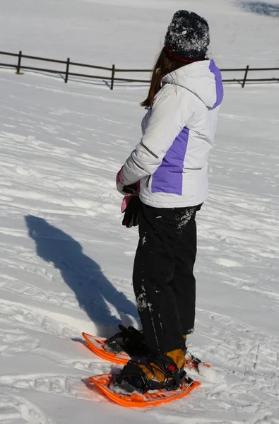 Girl with sportwear and orange snowshoes — Stock Photo, Image