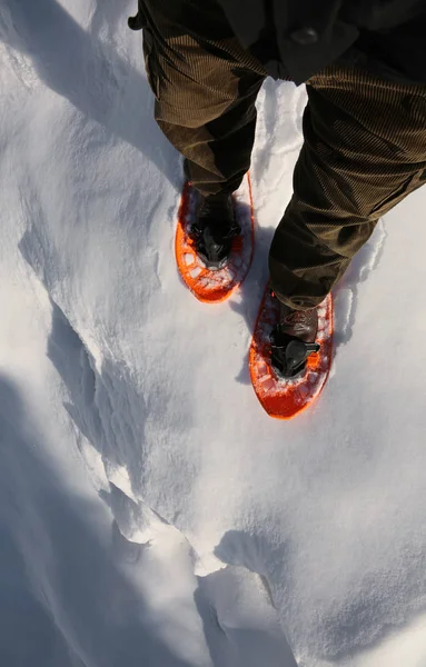 Hombre con raquetas de nieve anaranjadas camina cerca de una grieta profunda —  Fotos de Stock