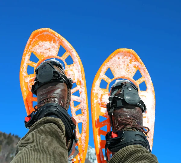 Duas sandálias de neve laranja no inverno e céu azul no fundo — Fotografia de Stock