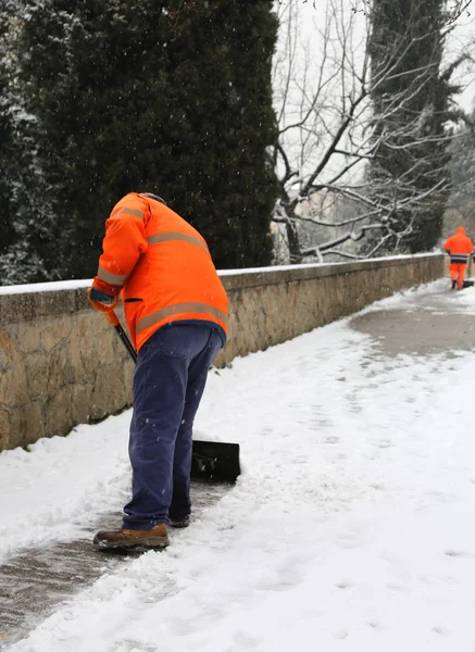 Мусорщик убирает снег с тротуара после сильного снега — стоковое фото