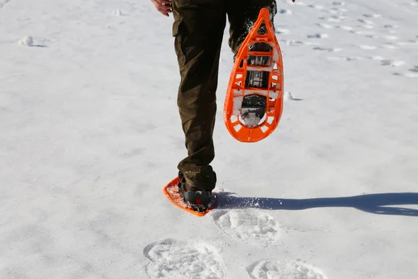 Boy runs with orange snowshoes and corduroy pants on white snow — Stock Photo, Image