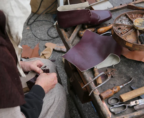 Szewc podczas naprawiania obuwia z kawałkiem skóry — Zdjęcie stockowe