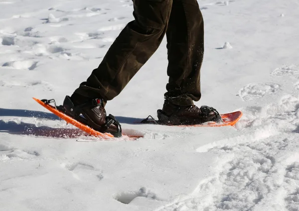 Homem anda com sapatos de neve laranja — Fotografia de Stock