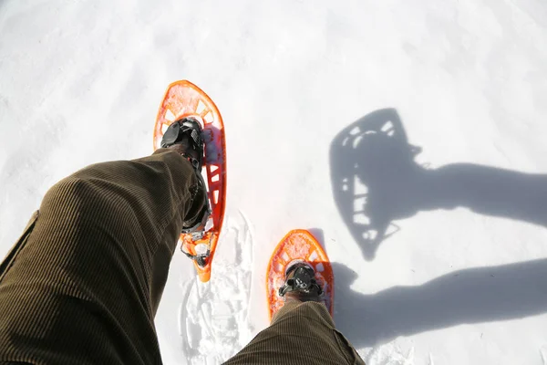 Dos patas de un joven que camina con raquetas de nieve anaranjadas —  Fotos de Stock