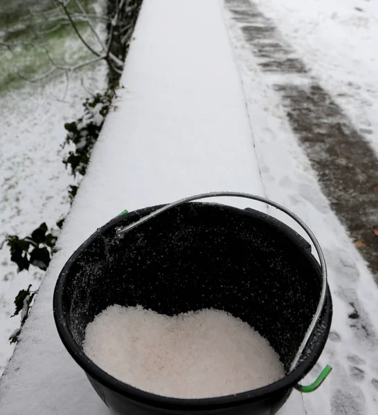 Bucket with salt to melt ice from the sidewalk and on the mounta — Stock Photo, Image