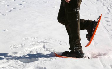 Kışın beyaz kar üzerinde kar ayakkabıları olan adam