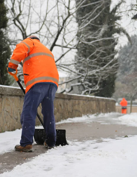 Lavoratore con giacca ad alta visibilità mentre spala neve — Foto Stock