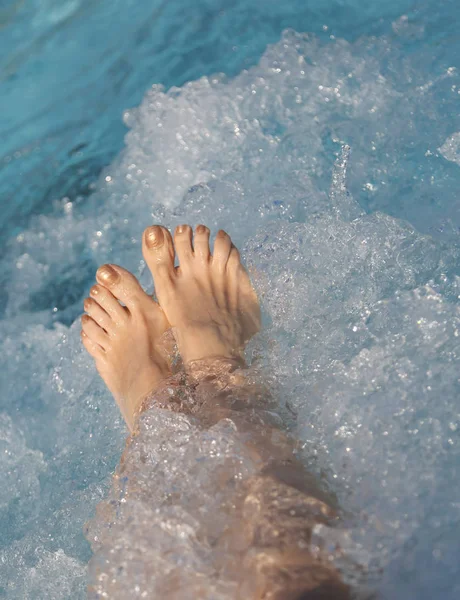 Pies de mujer durante la terapia de hidromasaje en la piscina de hidromasaje —  Fotos de Stock