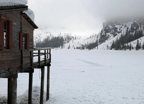 Chůda dům na zamrzlé jezero pokryté sněhem v zimě — Stock fotografie