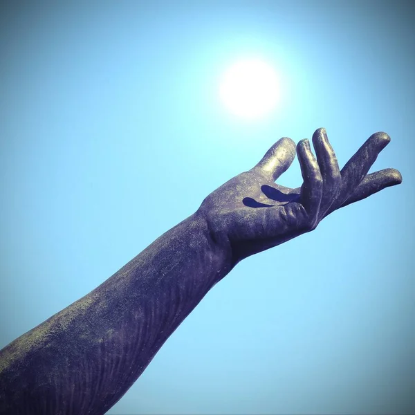 Main de statue essayant d'attraper le soleil blanc dans le ciel — Photo