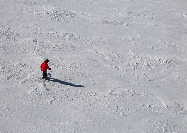 Uno sciatore in pista con neve e vestiti rossi — Foto Stock