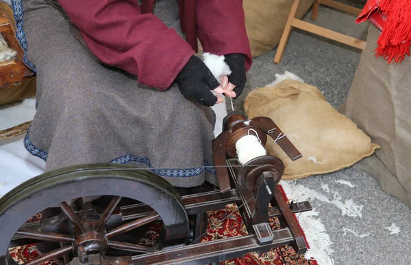 Bejaarde vrouw naaien een wollen jurk met behulp van een spinnewiel — Stockfoto