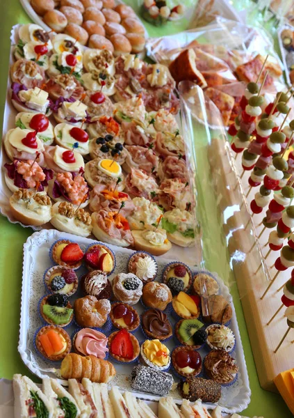 Buffet con muchas bandejas llenas de pasteles dulces y sándwiches —  Fotos de Stock