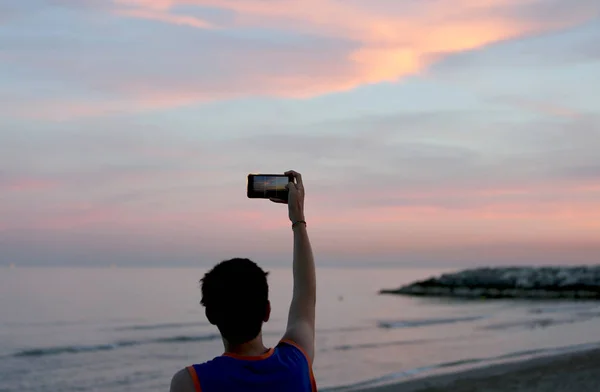 Ragazzo fotografa il bellissimo tramonto con uno smartphone — Foto Stock