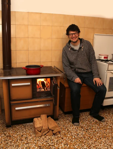 Young boy with old wood burning stove cooker in the kitchen — Stock Photo, Image