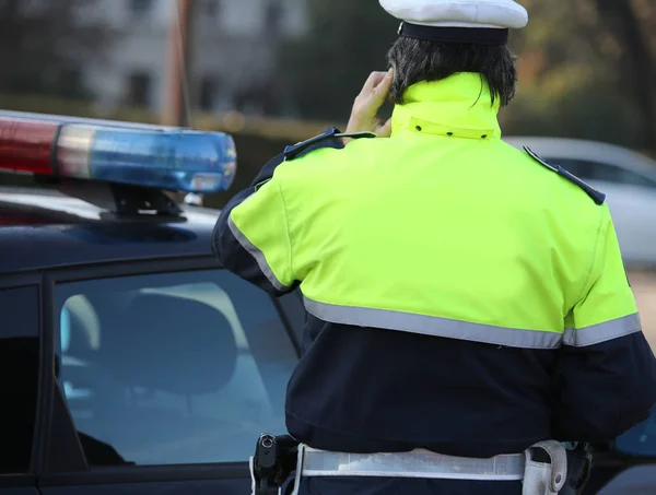 Policial em um casaco enquanto fala ao telefone para lidar com um em — Fotografia de Stock